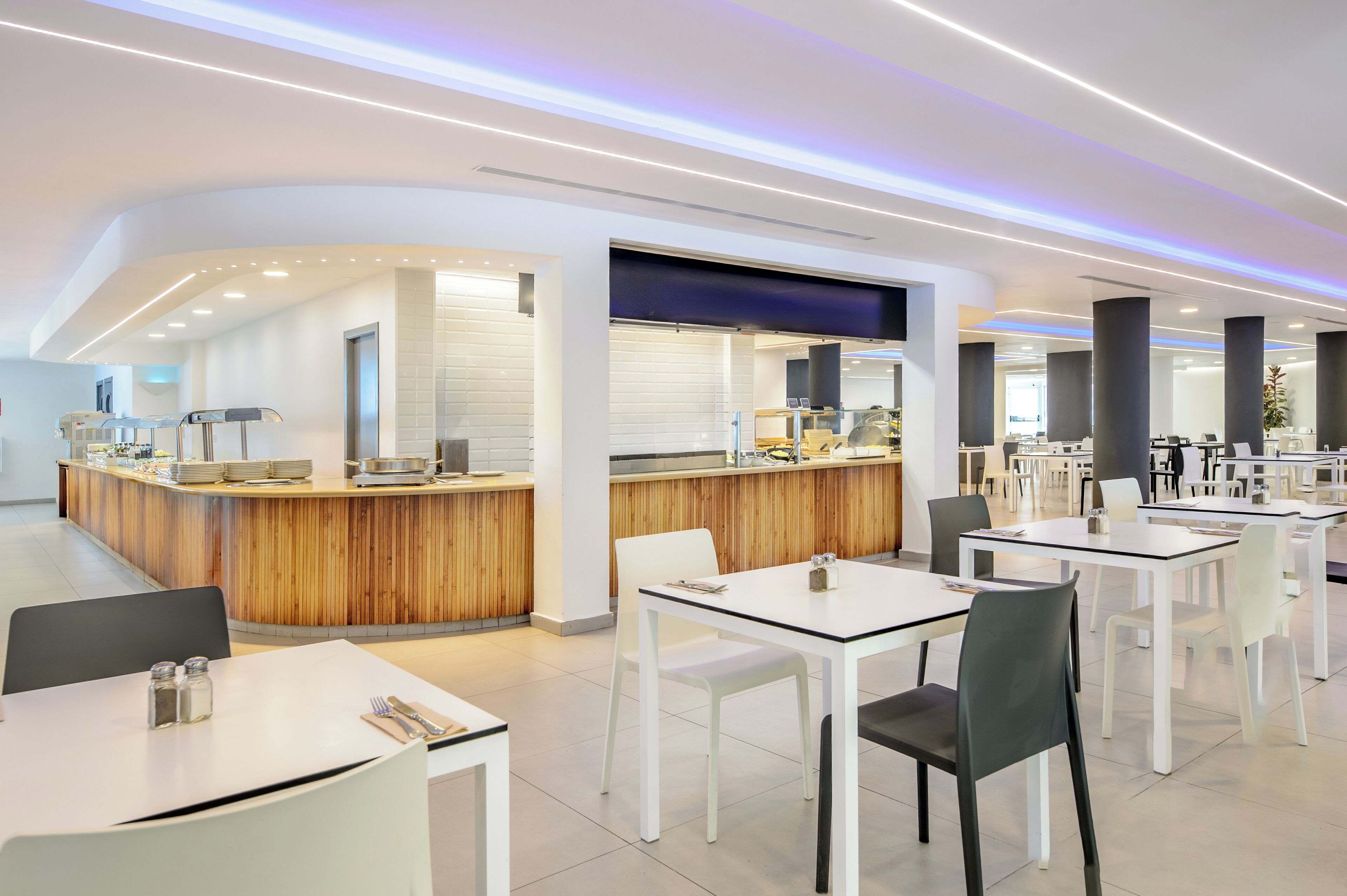 Un restaurant moderne avec un comptoir central, des tables et des chaises blanches.