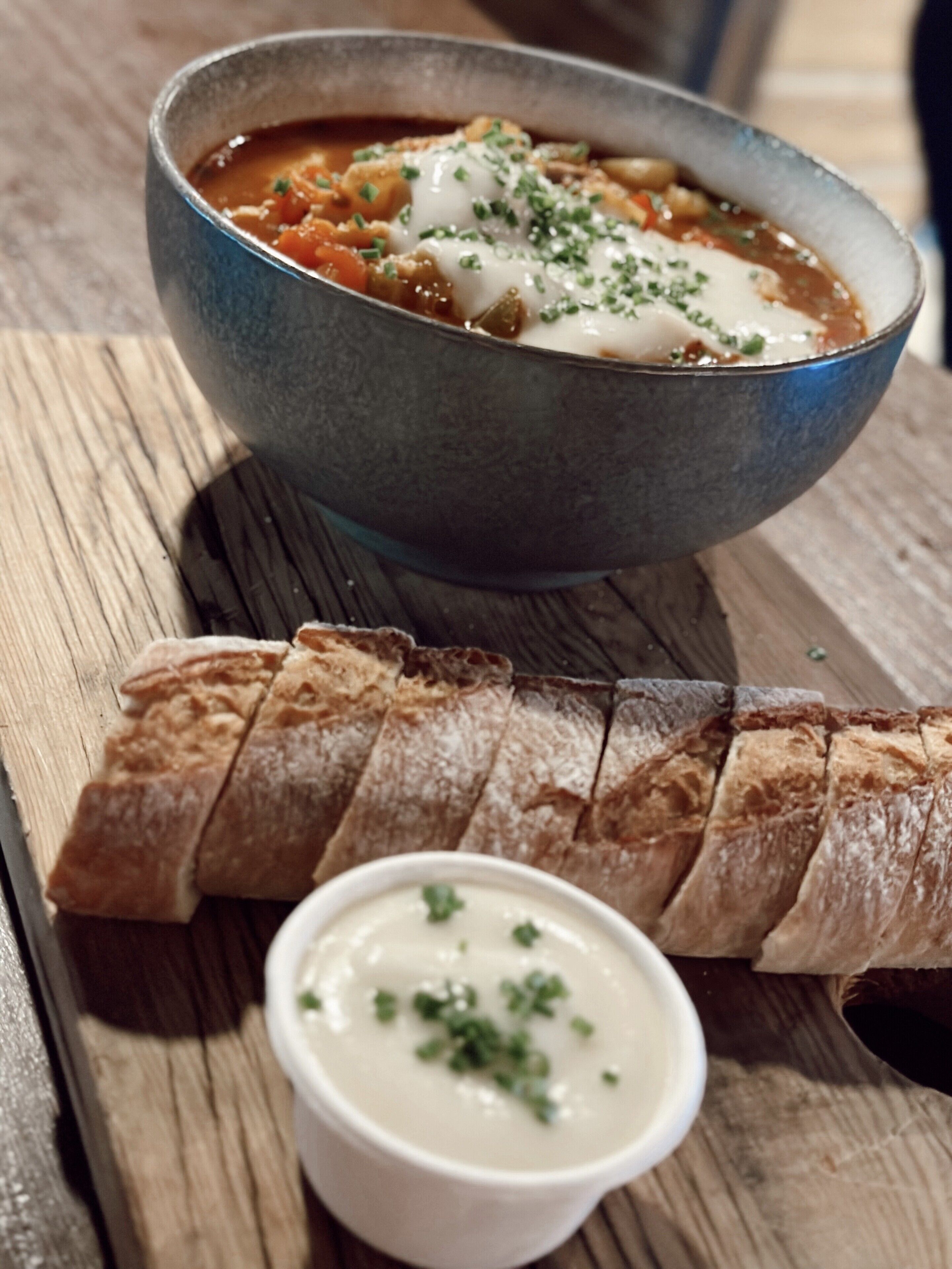 Un bol de sopa amb pa i un bol petit de salsa.