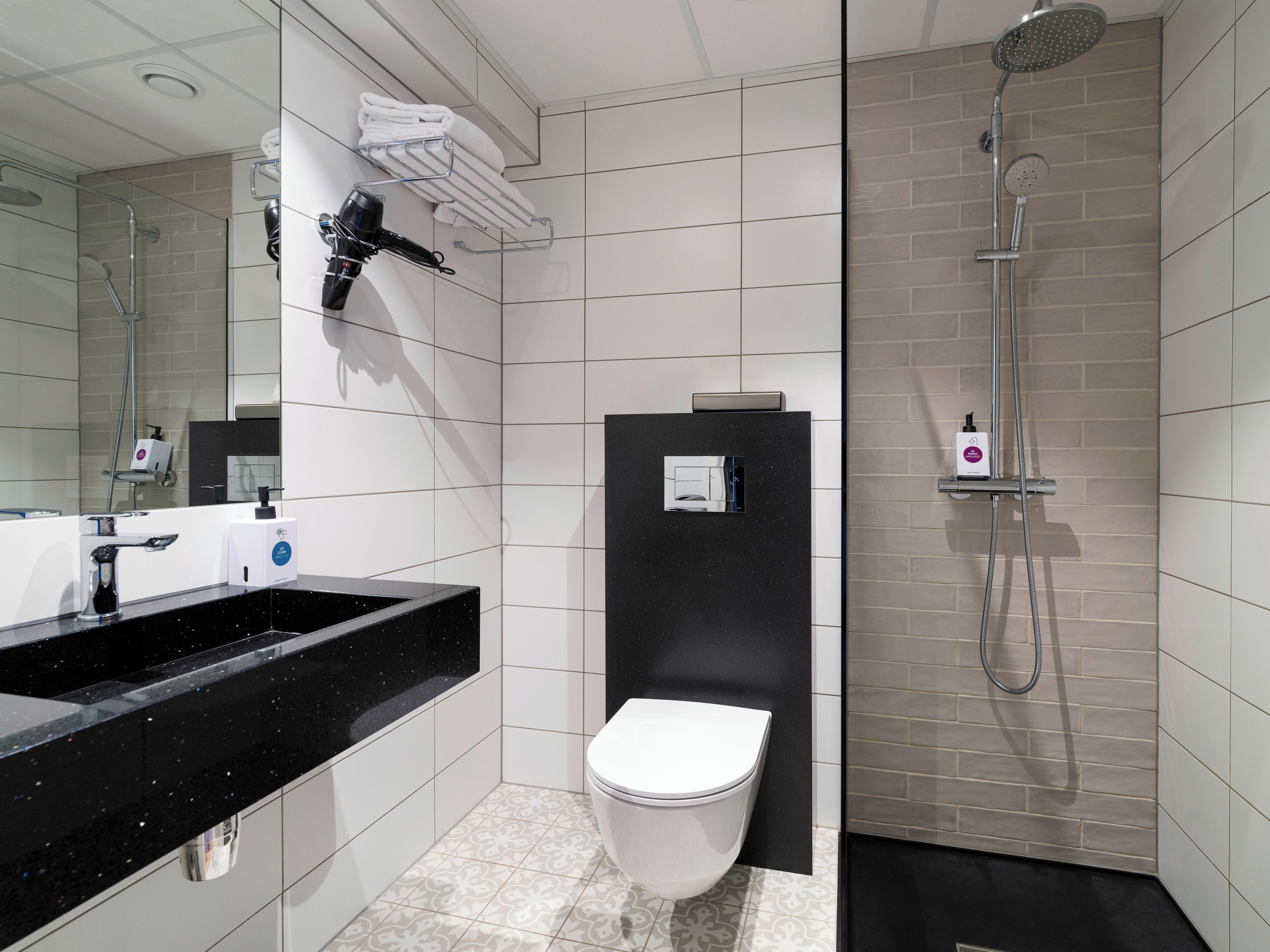 A modern bathroom with a black sink, white toilet, and a shower area.