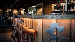 Un bar con taburetes de madera y un recorte metálico en la pared.