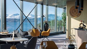 Un restaurante con amplios ventanales que ofrecen vistas a montañas nevadas.