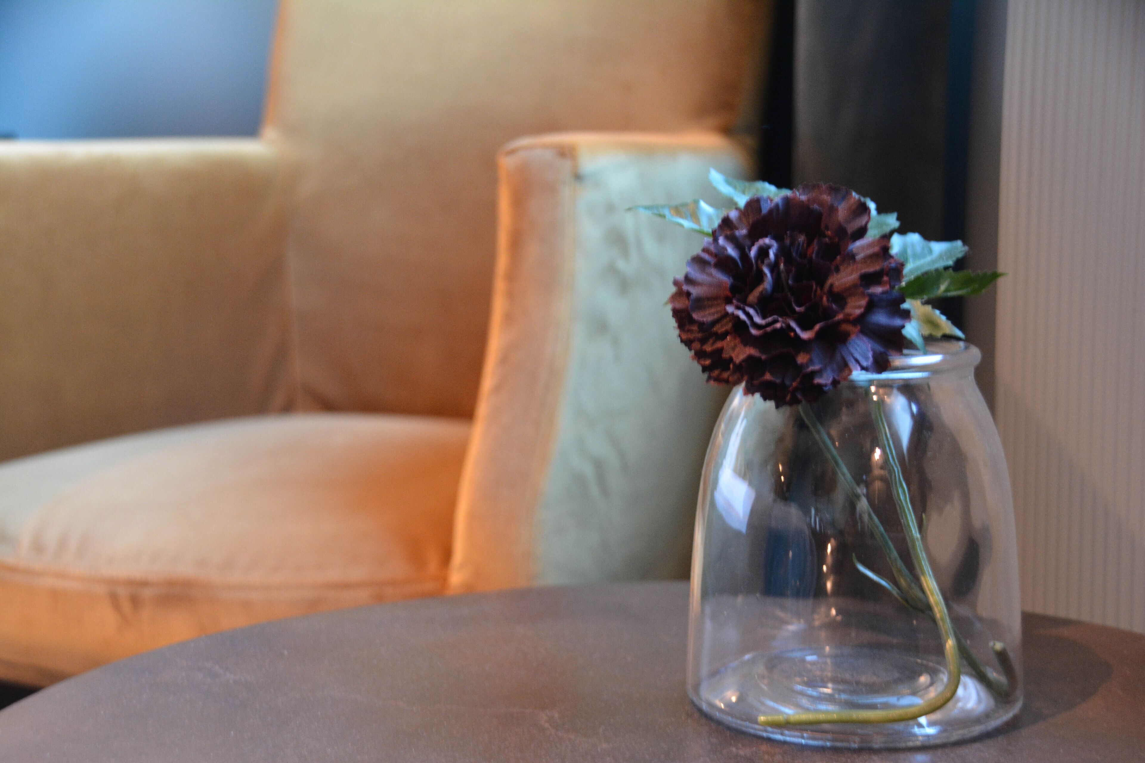 A clear glass vase with a single flower on a round table.