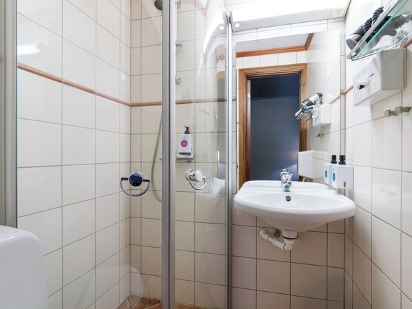 A bathroom with a glass shower enclosure, a white sink, and a mirror above it. - Quality Hotel Grand Royal (Narvik)