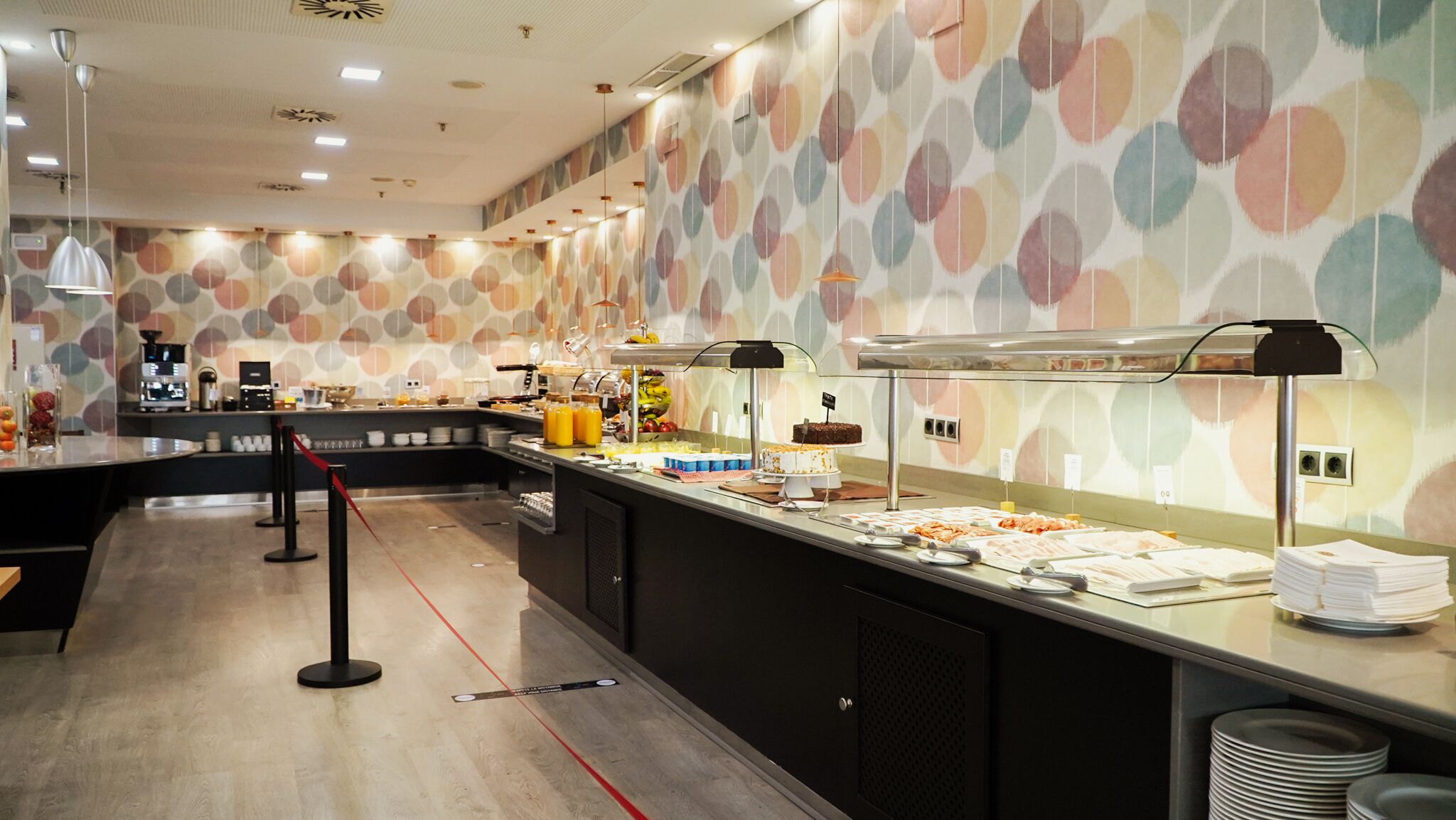 Un área de bufé con diversas opciones de comida, una máquina de café y un revestimiento de pared con diseño.