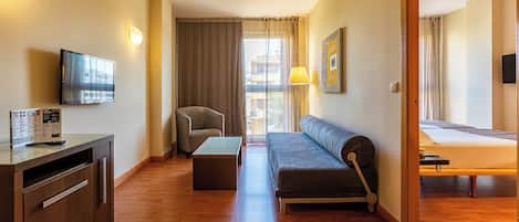 Une chambre d’hôtel moderne équipée d’un canapé, d’une télévision, d’un bureau et d’un lit.