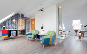 A modern living room with a loft bedroom, a kitchenette, and a dining area. - Hotel Vértice Sevilla (Seville)