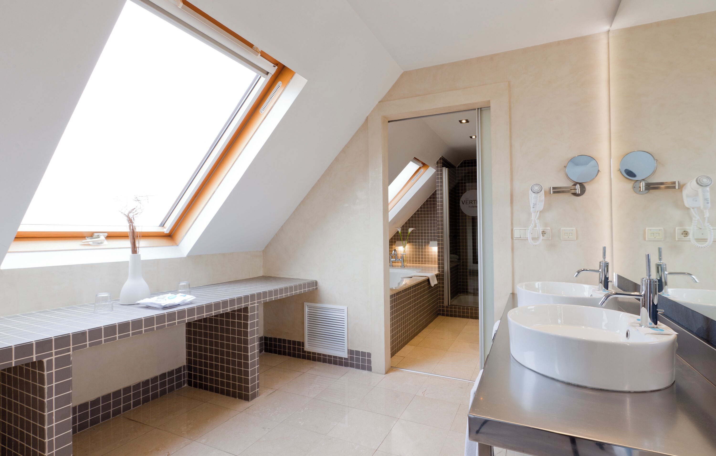 A modern bathroom with skylights, two sinks, and a walk-in shower.