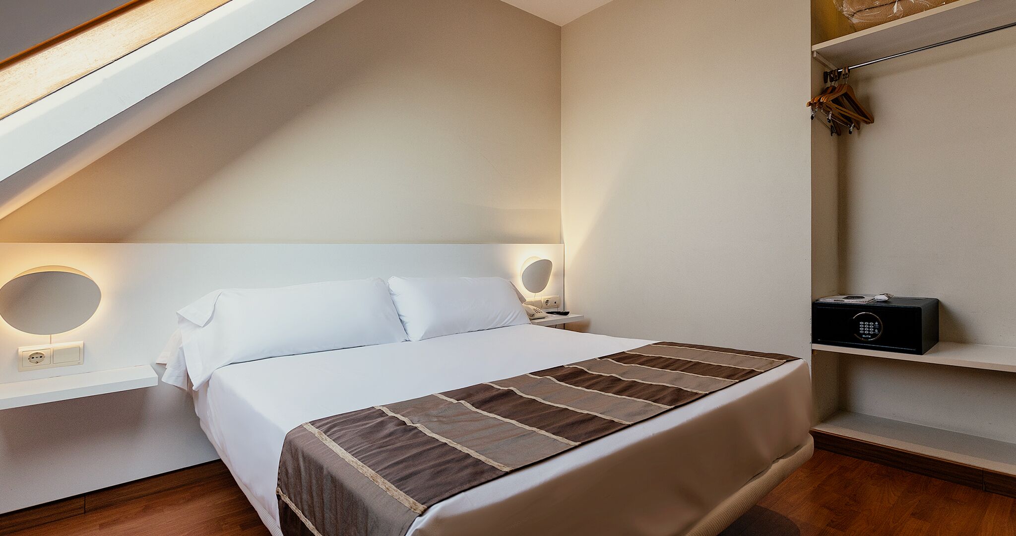 A neatly arranged bedroom with a bed, bedside tables, and a wall-mounted shelf.