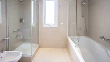 Un baño moderno con ducha envuelta en vidrio, bañera independiente y lavamanos sobre pedestal.
