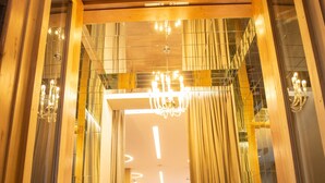 Un pasillo con suelo de madera, un candelabro y un comedor con mesas y sillas.