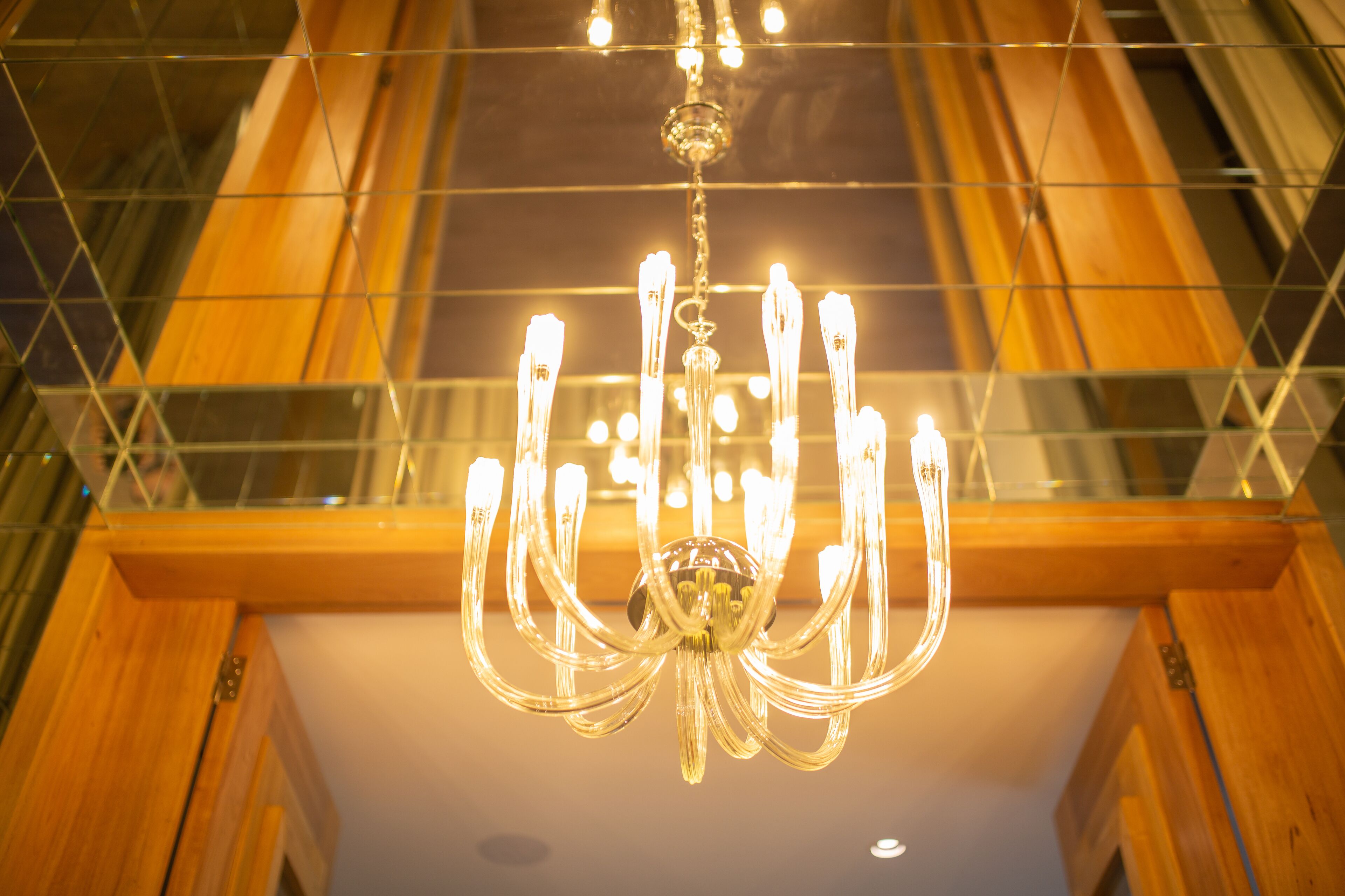 Un candelabro con varias lámparas colgando del techo en una habitación con paneles de madera y baranda de cristal.