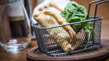 A basket containing a pastry and greens on a wooden coaster.