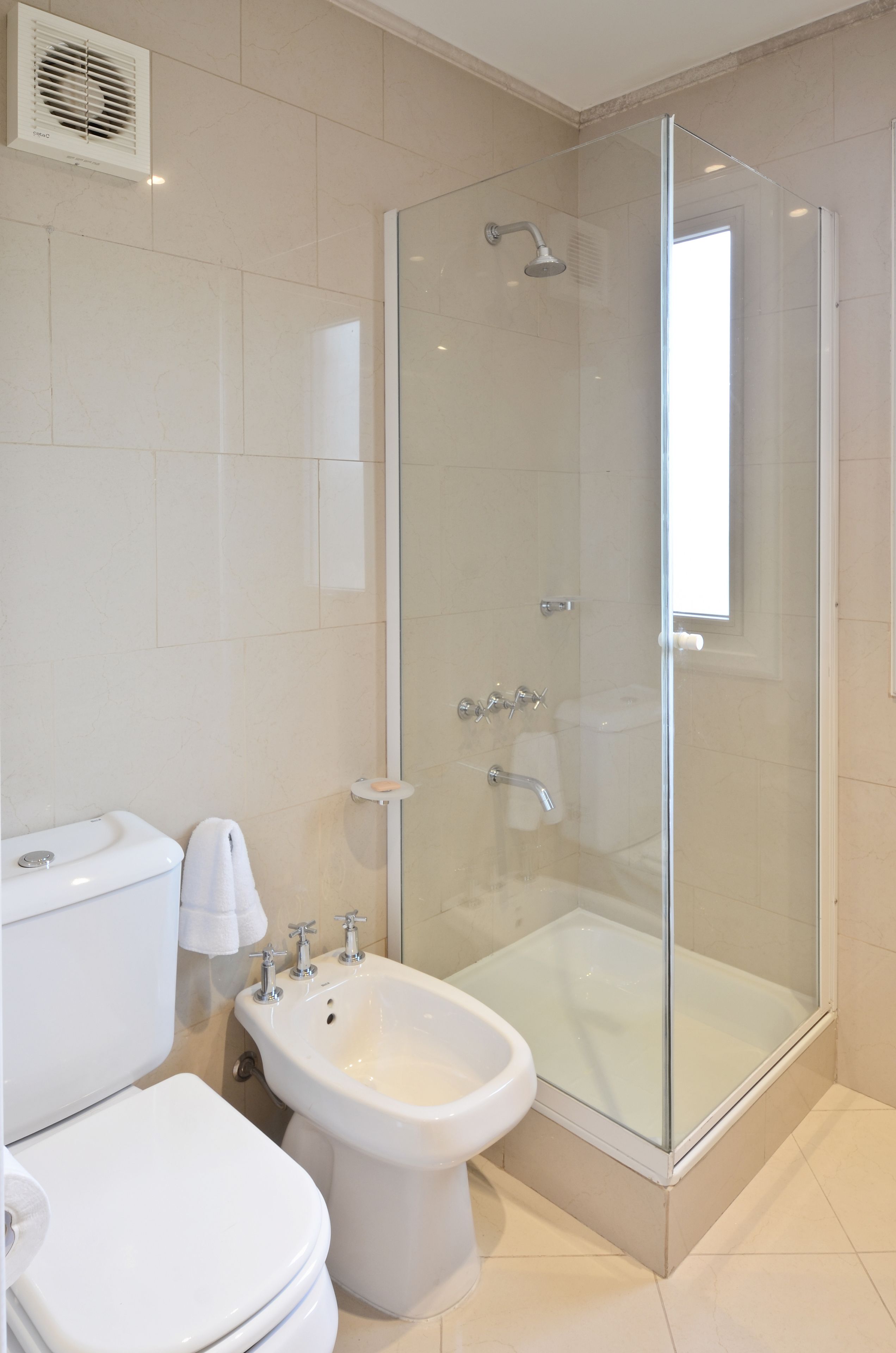 A bathroom with a glass-enclosed shower, a bidet, and a toilet.