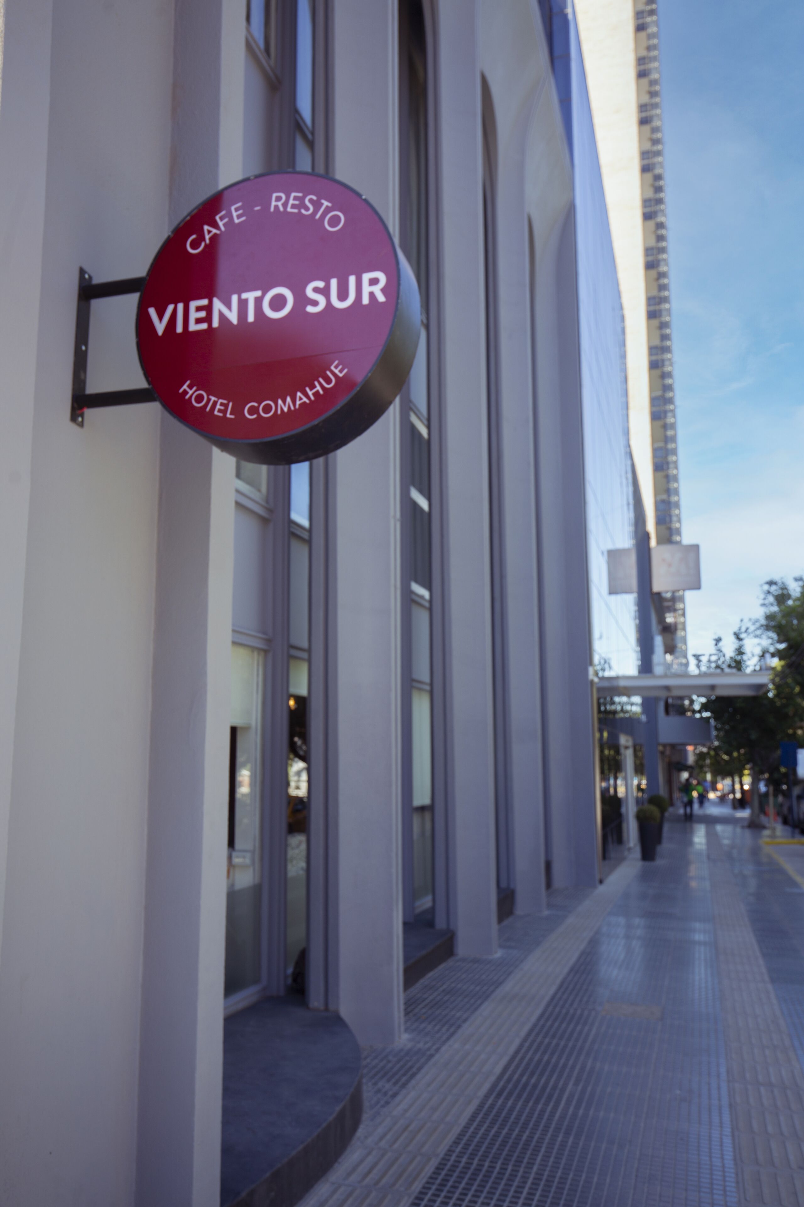 A sign for "Café - Resto Viento Sur Hotel Comahue" on a building's exterior.