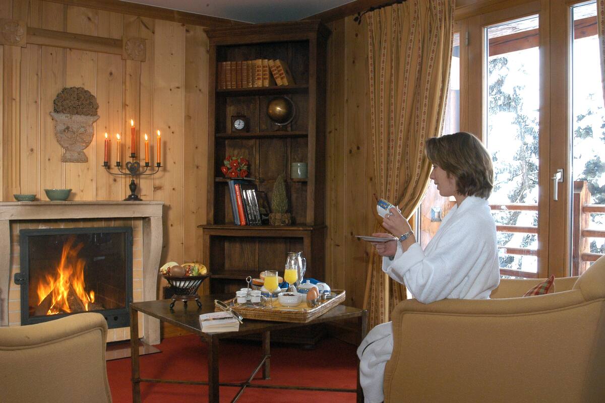 A cozy room with a fireplace, a bookshelf, and a breakfast tray on a table.