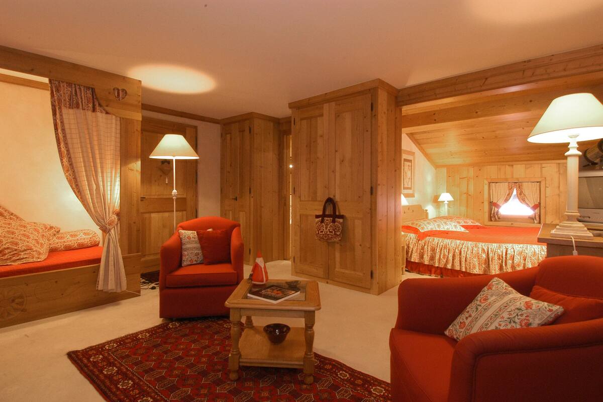 A cozy room with wooden walls, a red sofa, a small table with a magazine, and a patterned rug.