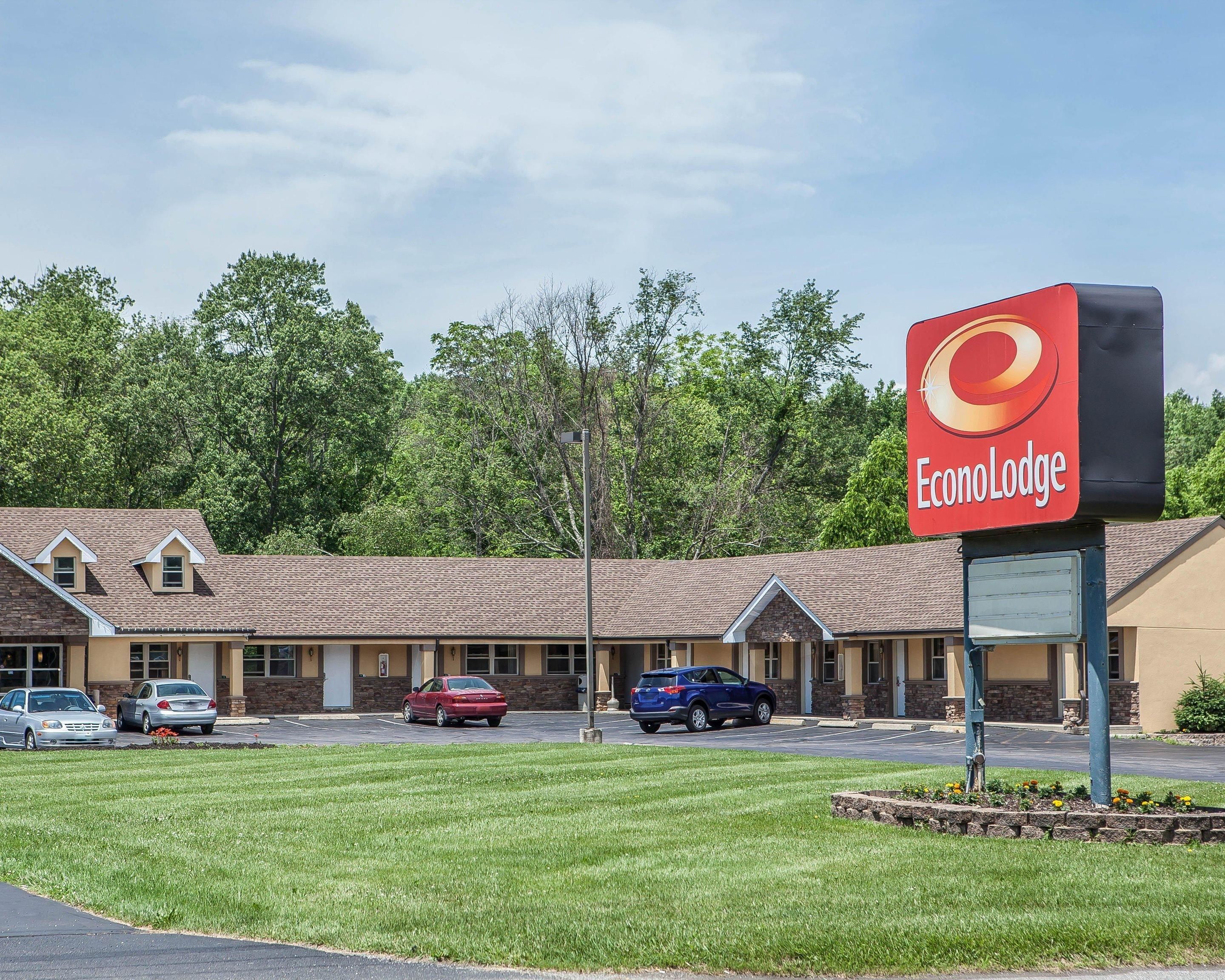 Un motel con un letrero rojo que dice 'EconoLodge', que presenta un edificio sencillo de dos pisos con techo de tejas y un estacionamiento al frente.