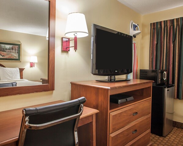 A hotel room with a bed, a desk with a chair, a television, a coffee maker, and a refrigerator. - Econo Lodge Newton (Newton)