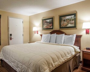 A hotel room with a large bed, two wall-mounted lamps, and two framed paintings above the bed. - Econo Lodge Newton (Newton)