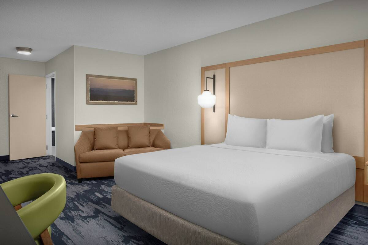 Une chambre d’hôtel avec un grand lit, un canapé, un bureau et une chaise.