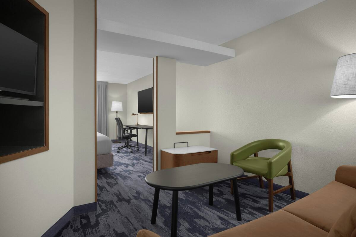 Une chambre d’hôtel avec un lit, un bureau, une chaise, une télévision et une lampe.