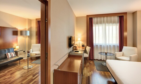 A hotel room with a sofa, armchairs, a small table, a TV, and a window with curtains. - Hotel Sercotel AB Rivas (Rivas-Vaciamadrid)