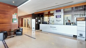 A hotel reception area with a modern design, including a reception desk, seating area, and a visible elevator. - Hotel Sercotel AB Rivas (Rivas-Vaciamadrid)