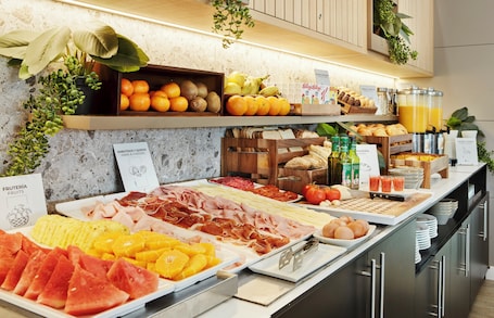 A buffet with various food items including fruits, cheeses, meats, and bread.. Hotel Sercotel AB Rivas