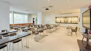 A conference room with multiple tables and chairs, a projector, and a large screen. - Hotel Sercotel AB Rivas (Rivas-Vaciamadrid)