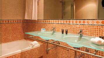 A bathroom with two glass sinks, a bathtub, and a shower.