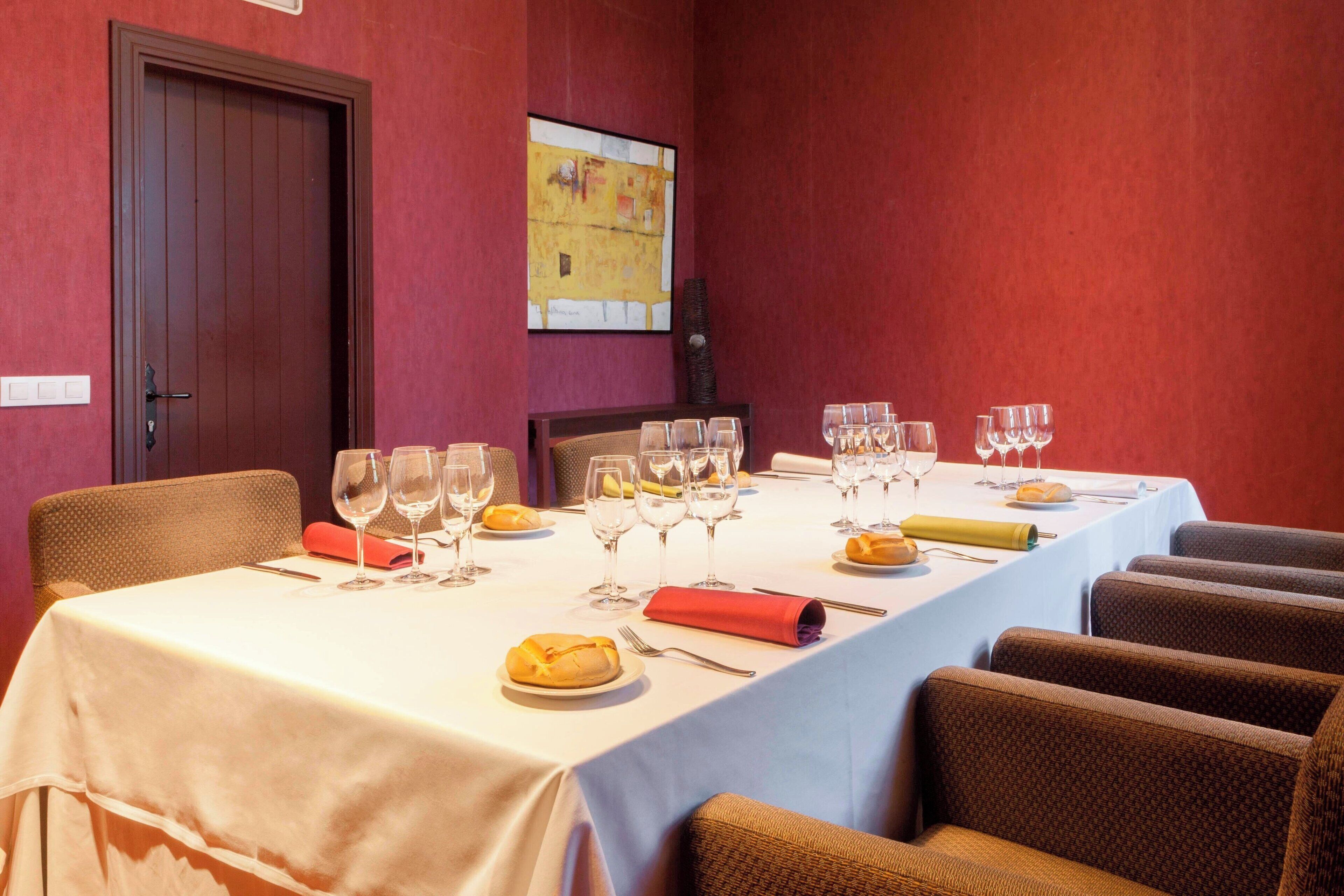 A dining room with a long table set for a meal, chairs, and a door.