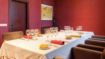 A dining room with a long table set for a meal, chairs, and a door.