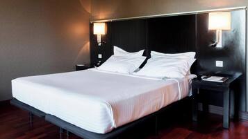 A hotel room with a large bed, two bedside tables, and wall-mounted lamps.