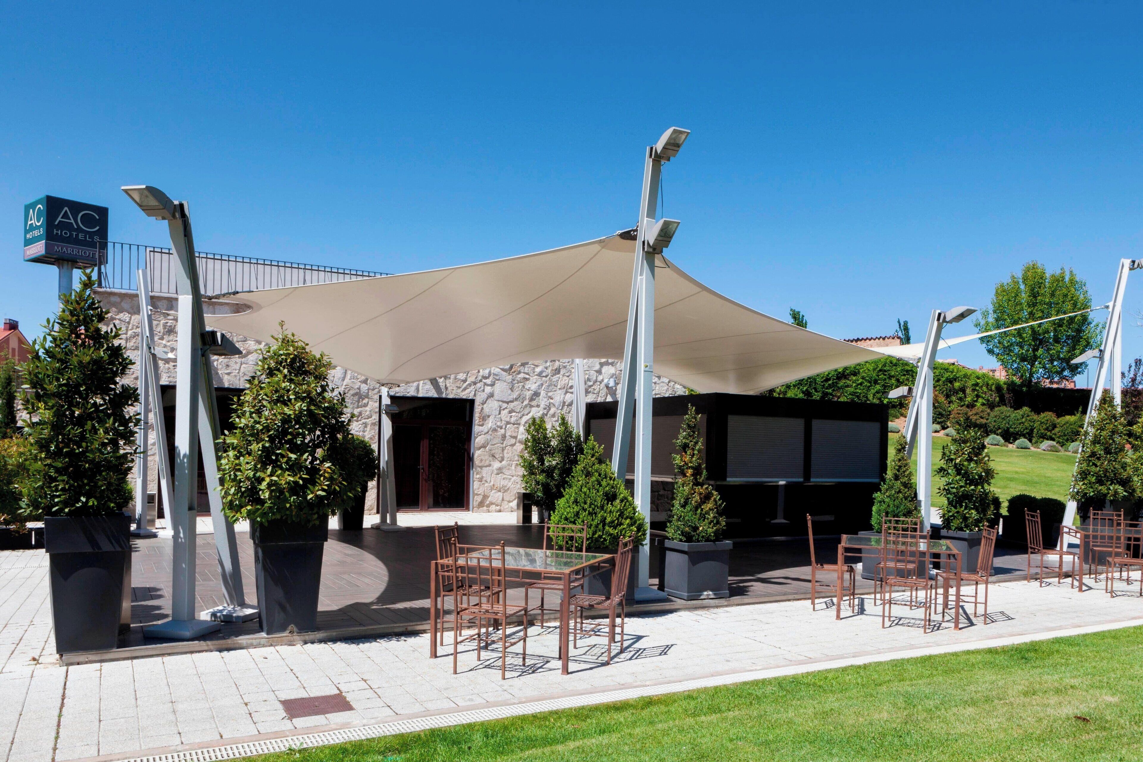 Un área de estar al aire libre con mesas y sillas, un toldo grande y un letrero del hotel Marriott.