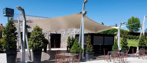 Un área de estar al aire libre con mesas y sillas, un toldo grande y un letrero del hotel Marriott.