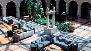 Ein großzügiger Außenbereich mit modernen Sofas und Tischen, umgeben von Backsteinbögen und viel Grün.