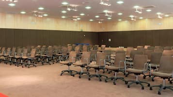 A conference room with rows of chairs, a carpeted floor, and ceiling lights.