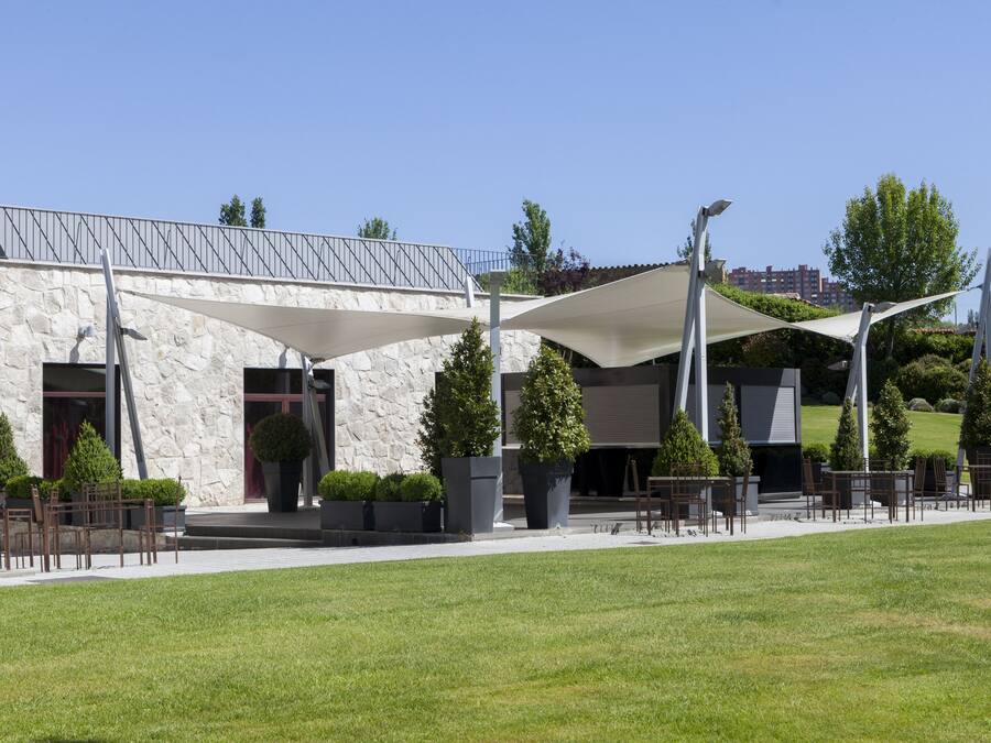 A modern building with a stone facade, outdoor seating area, and a covered patio.
