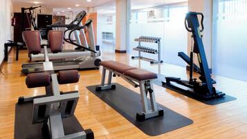 Una palestra con macchinari cardio, panche per pesi e manubri.