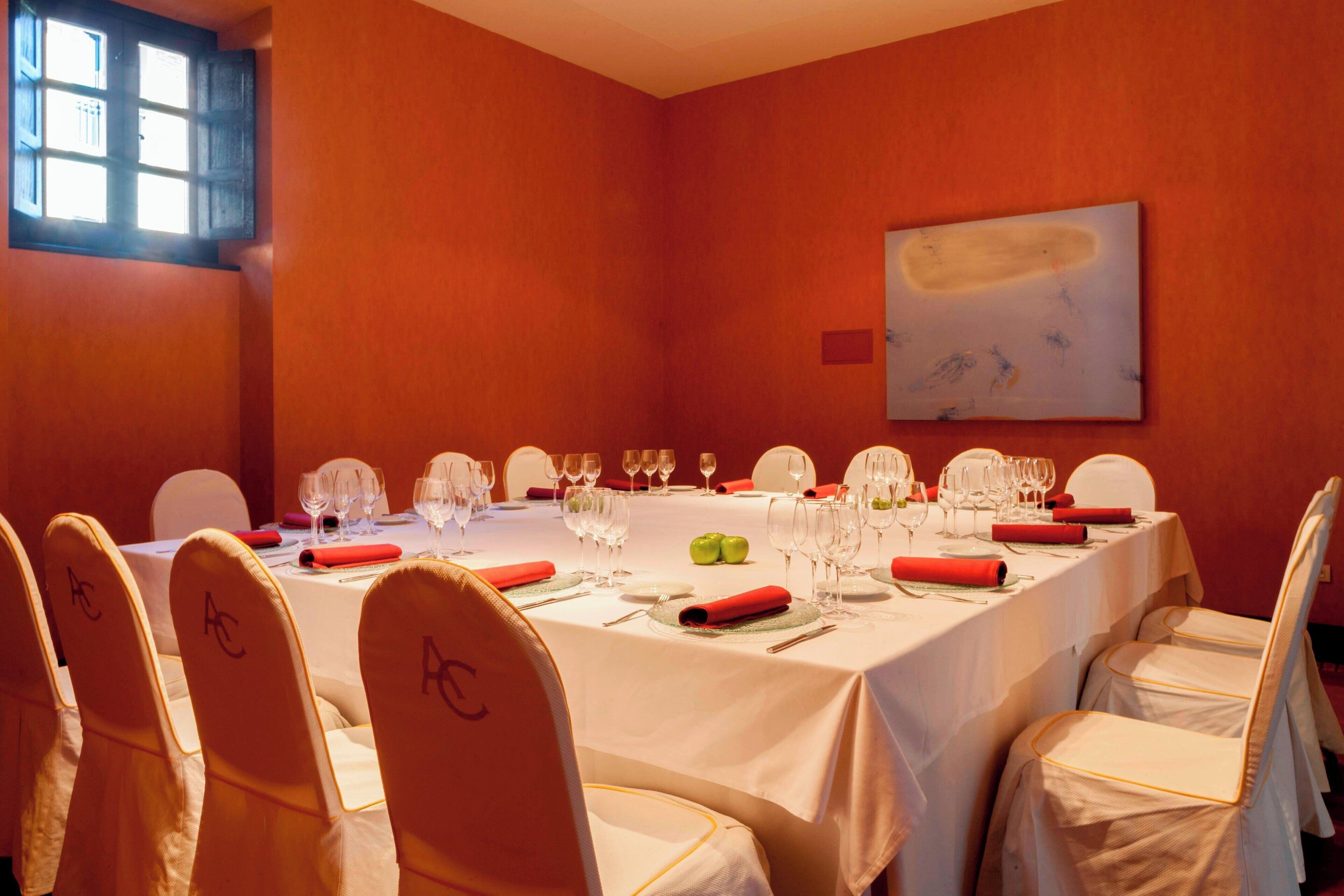 A conference room with a long table set for a meeting, chairs with name tags, and a painting on the wall.