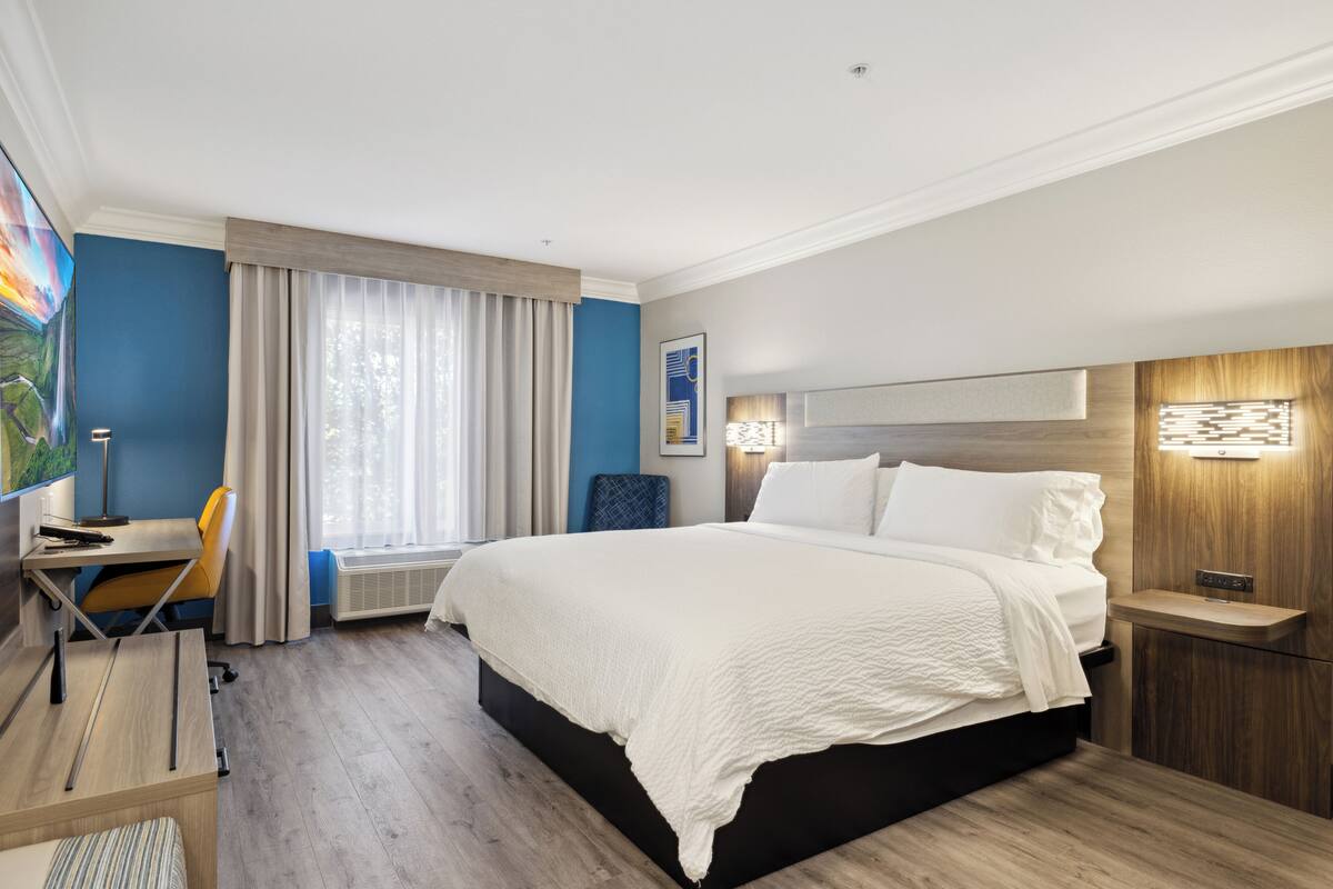 Ein modernes Hotelzimmer mit einem großen Bett, einem Schreibtisch und einem Sessel.
