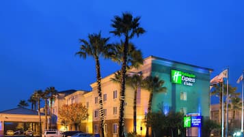 A Holiday Inn Express building with a sign, palm trees, and parked cars.