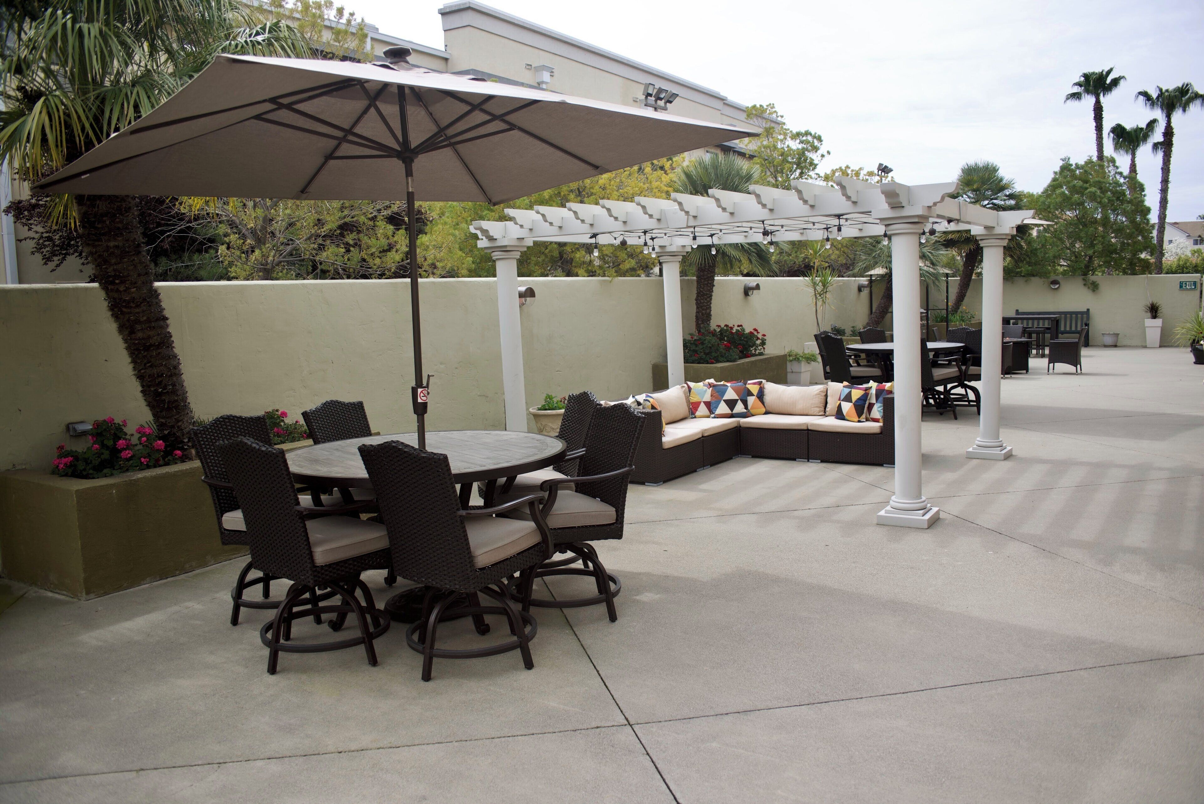 An outdoor patio with a round table and chairs, a covered seating area, and a pergola.