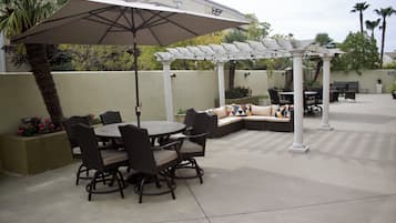 An outdoor patio with a round table and chairs, a covered seating area, and a pergola.