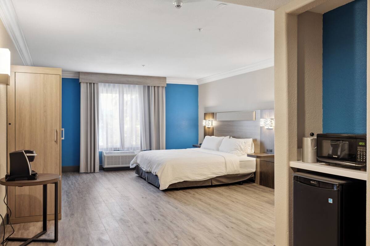 Ein Hotelzimmer mit Bett, Nachttisch, Mikrowelle und kleinem Kühlschrank.