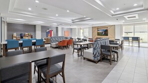 A modern dining area with multiple seating options, including tables and booths, and a counter with beverages. - Holiday Inn Express Hotel & Suites Vacaville by IHG (Vacaville)