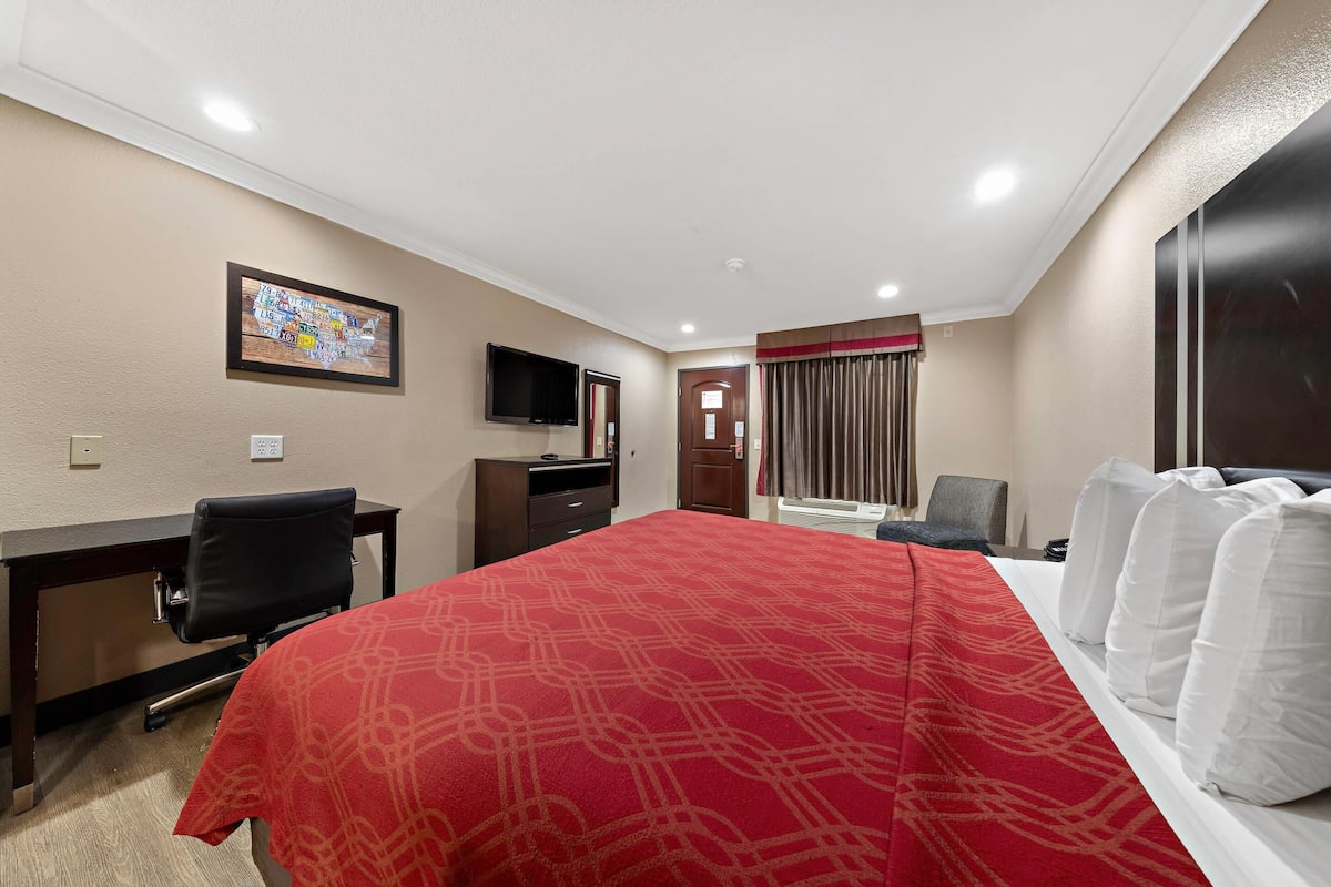 Une chambre d’hôtel avec un lit, un bureau, une chaise, une télévision et une porte.