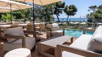Een terras met tuinmeubilair, een zwembad en uitzicht op zee.