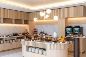 A modern breakfast bar with a marble backsplash, a variety of food items, and a coffee station. - Radisson Hotel Cannes Seaside (Cannes)