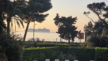 Zona junto a la piscina con sillones reclinables, una piscina pequeña y vista al mar con un crucero en la distancia.